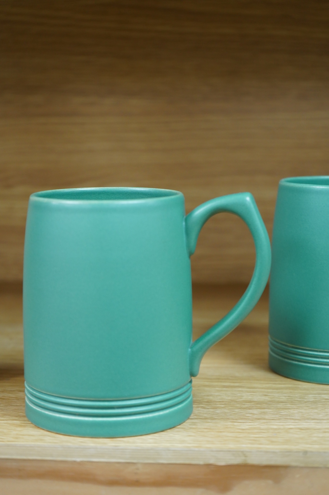 A pair of Keith Murray for Wedgwood green monochrome tankards, 12cm high